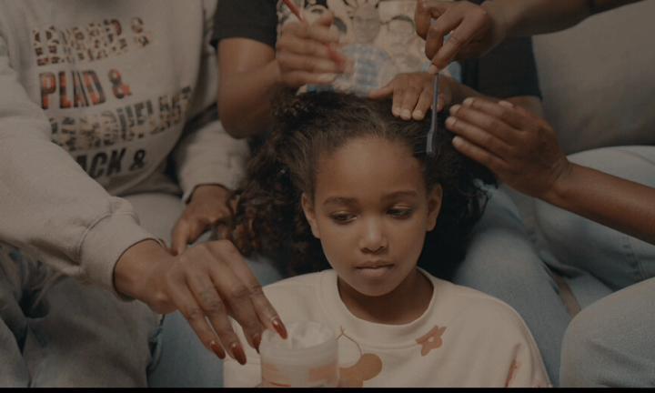little girl getting her hair done by three women
