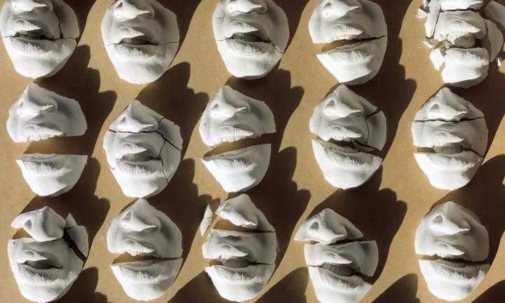 Photo of three rows of clay mouths and noses, cracked into pieces.