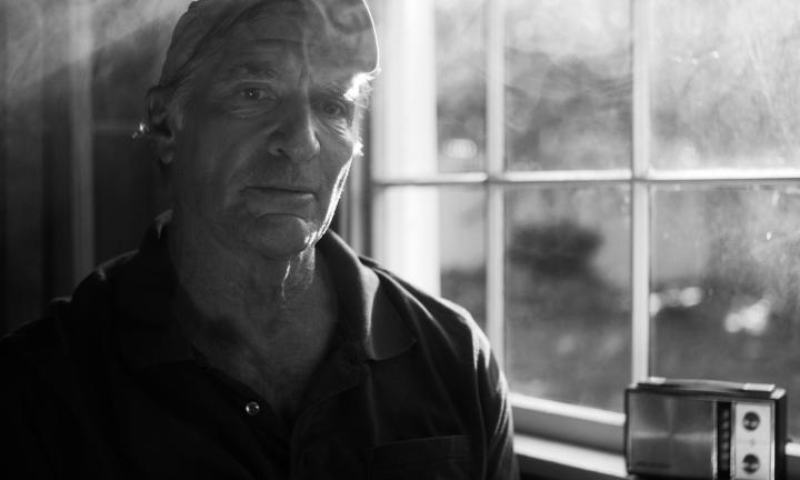 man in ball cap by window with old-fashioned radio on the windowsill