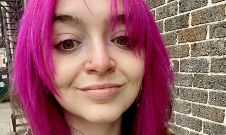 close-up of poet Amy Gaeta with pink hair with a brick wall in the background