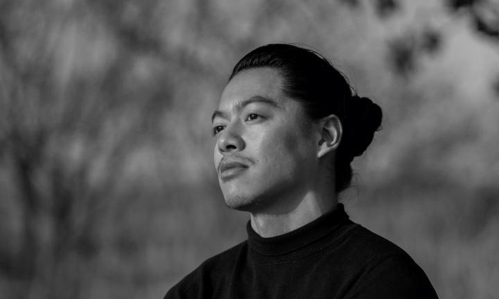 black and white photo of poet John Paul Martinez in a field looking left