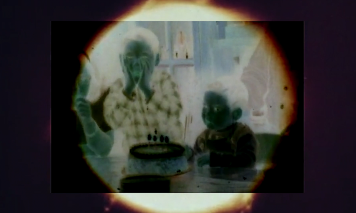 Photo negative of two children next to birthday cake.