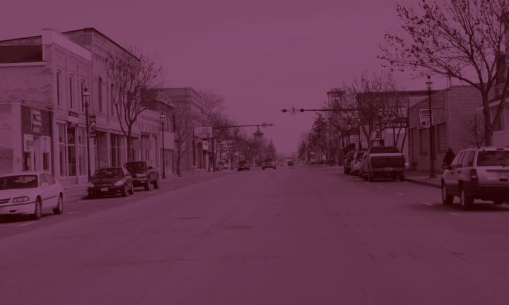 Omro Main St Historic District wide street with cars parked on either side, photo tinted pink