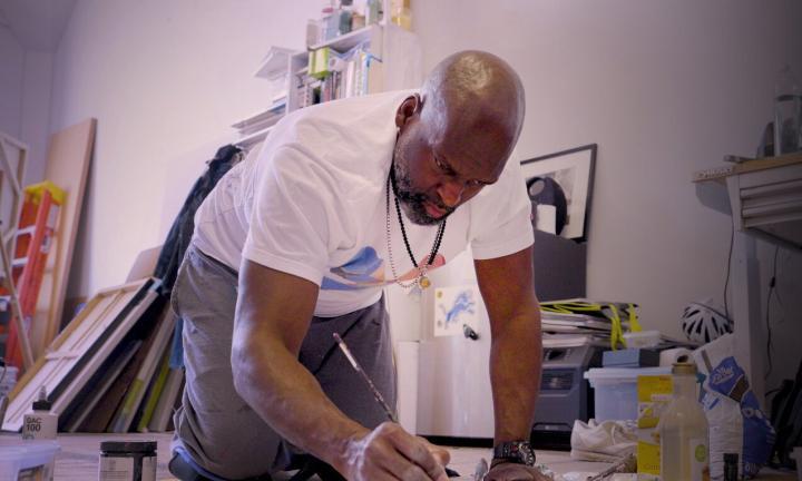 man painting on a canvas on the floor