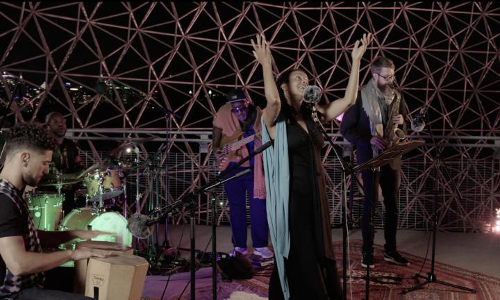 woman with upraised hands in the biosphere surrounded by musicians