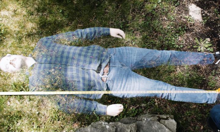 transparent man lying on grass with unspooled tape measure