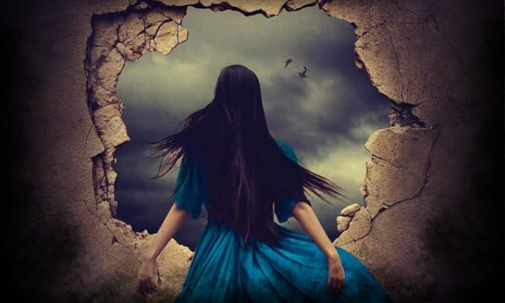 Woman standing in front of hole in wall with her arms thrown back