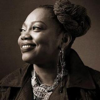 Dee Alexander smiling Black woman looking to the right with long earrings and necklace