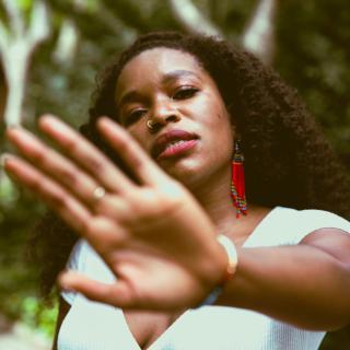 Young woman with red beaded earrings putting her hand in front of the camera