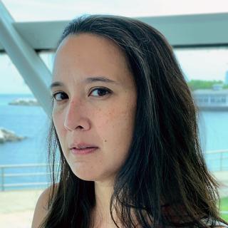 Jennifer Nelson poet, woman looking at camera with blue water behind her