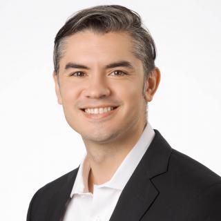 Portrait of the writer with a black suit jacket and white dress shirt.