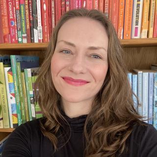 author posing in front of colorful bookshelves