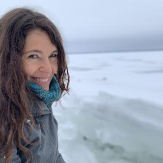a woman smiling beside a frozen lake