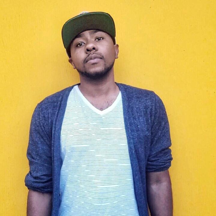 Cortney Lamar Charleston man in blue sweater standing in front of yellow wall